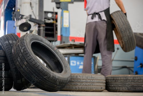 A male car mechanic changing tires In the process of checking the condition of 4 new tires in the tire shop to change the wheels at the service center or auto repair shop for the car industry
