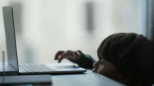 Little child using computer laptop at home learning to use modern technology device. Candid lifestyle of small boy in front of screen