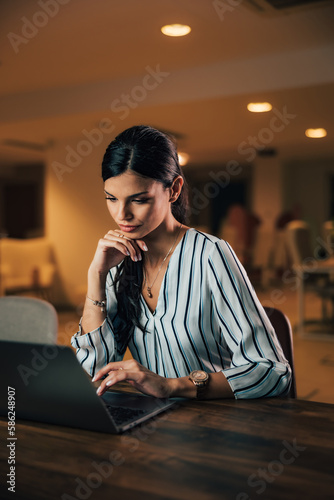 Staid businesswoman typing on a laptop, sitting at the office.