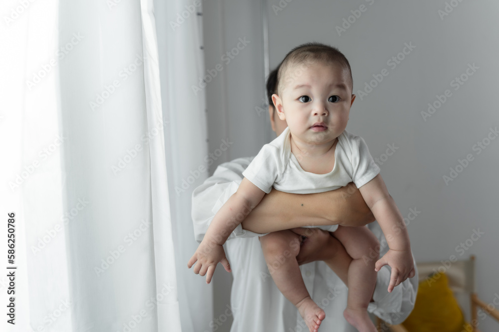 Asian young father working from home while holding his baby boy and smiling while making a break from his work. Asian young father working from home while holding his baby boy and smiling while making a break from his work.