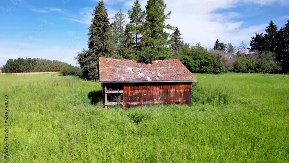 Orbiting around a old barn surrounded by green grass under a blue sky with high voltage power lines in the background Orbiting around a old barn surrounded by green grass under a blue sky with high voltage power lines in the background