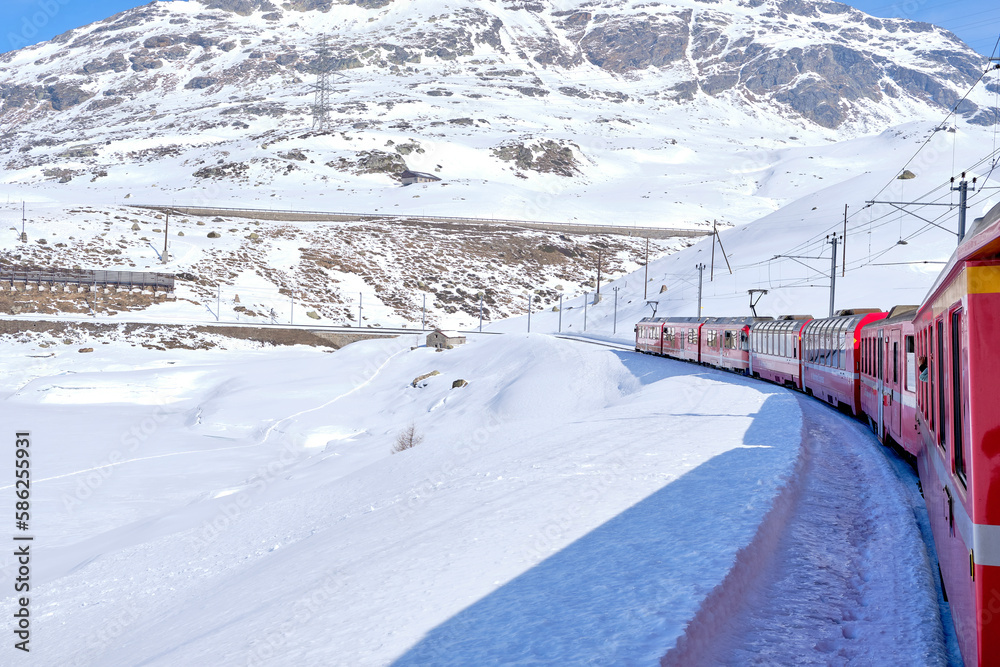 Obraz premium Bernina mountain pass. The famous red train is crossing the white lake. Amazing landscape of the Switzerland land. Famous destination and tourists attraction