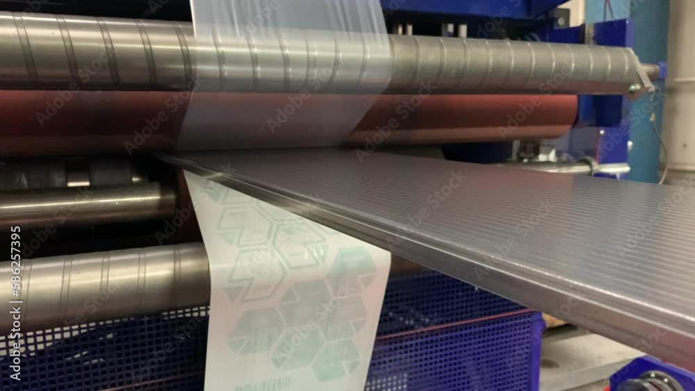 Application of protective films on plastic sheets on machine at factory. Production of polycarbonate panels. Placing information about product