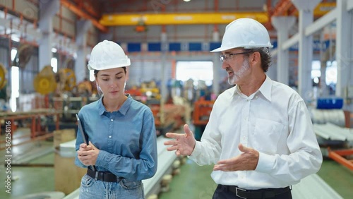 Two professional engineer man and woman manager leader wearing helmet walking in factory talking and discussing for work