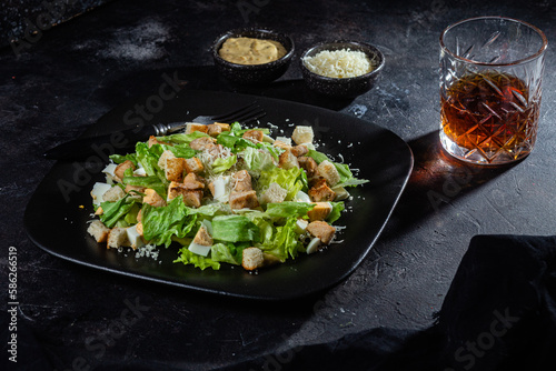 Caesar salad on a black plate close-up