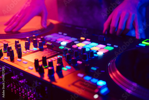 Close up of DJ hands on dj console mixer during concert in the club