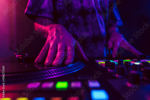 Close up of DJ hands on dj console mixer during concert in the club