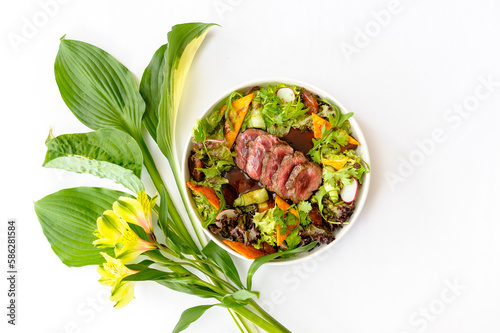 Salad with medium roasted beef and greens on a white background