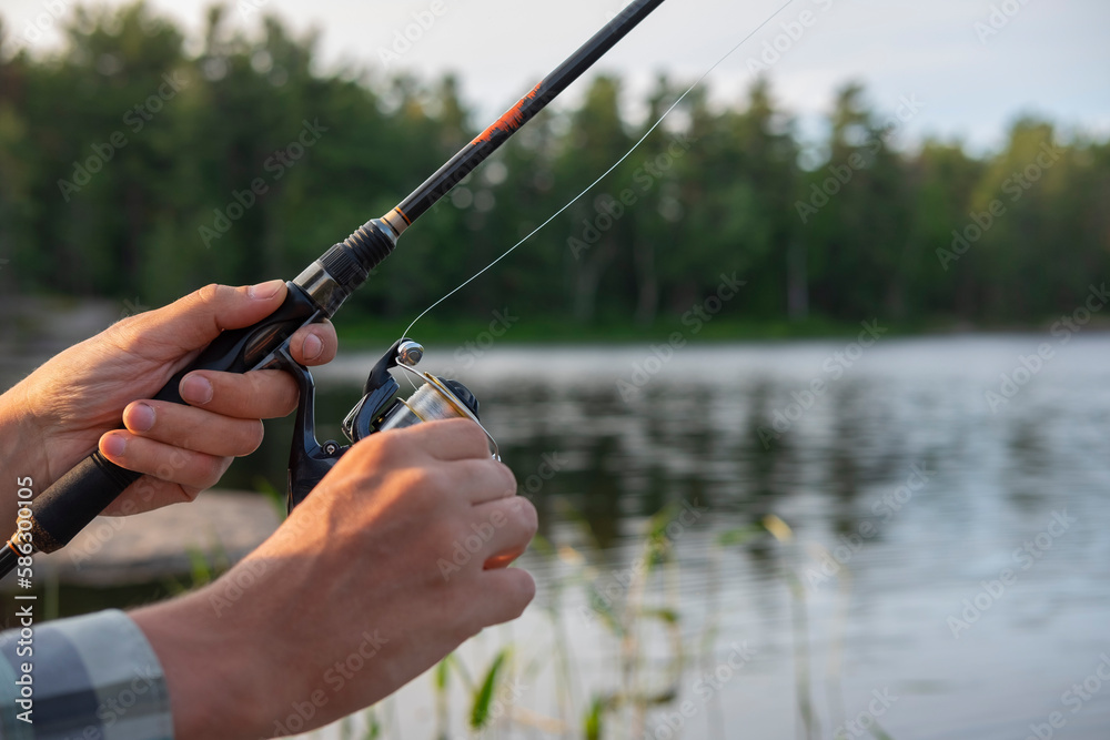 Close up of a man's hand holding a fishing rod. Sunset soft light