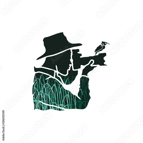 silhouette of a wildlife photographer with a bird perched on the edge of the lens