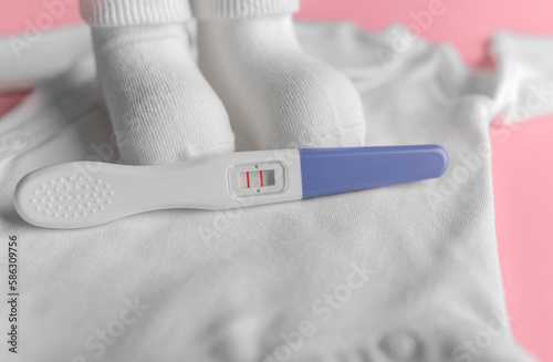 Pregnancy test. Still life on the background of children's clothes.