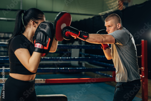 A man practices attack in boxing wit a help of a woman holding pads