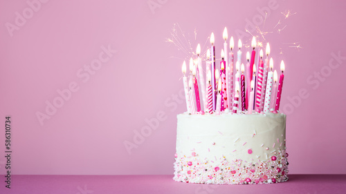 Pink birthday cake with many pink birthday candles and sparklers