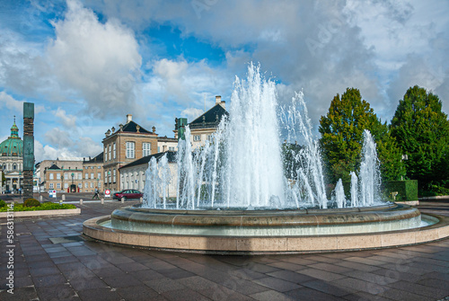 Copenhagen, Denmark - September 13, 2010: Landscape, Central fountain spouting white water into blue cloudscape, located at Amaliehaven garden. Dome of Frederiks Church and Amalienborg