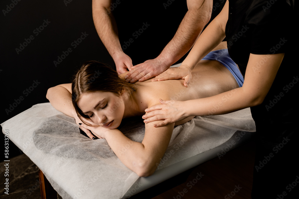 Obraz premium 4 hands massage in spa. Two masseurs are making four hands relaxing massage with oil for girl. Relaxation. Manual therapy.