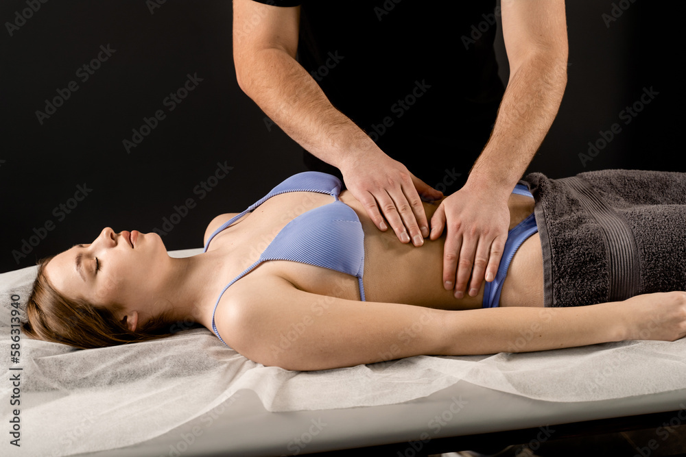 Fototapeta premium Belly anti cellulite massage spa procedure for young girl. Attractive girl is relaxing on classic massage in spa.