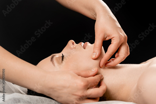 Face massage close-up. Masseur is making facial beauty treatments for attractive female model. Relaxation.