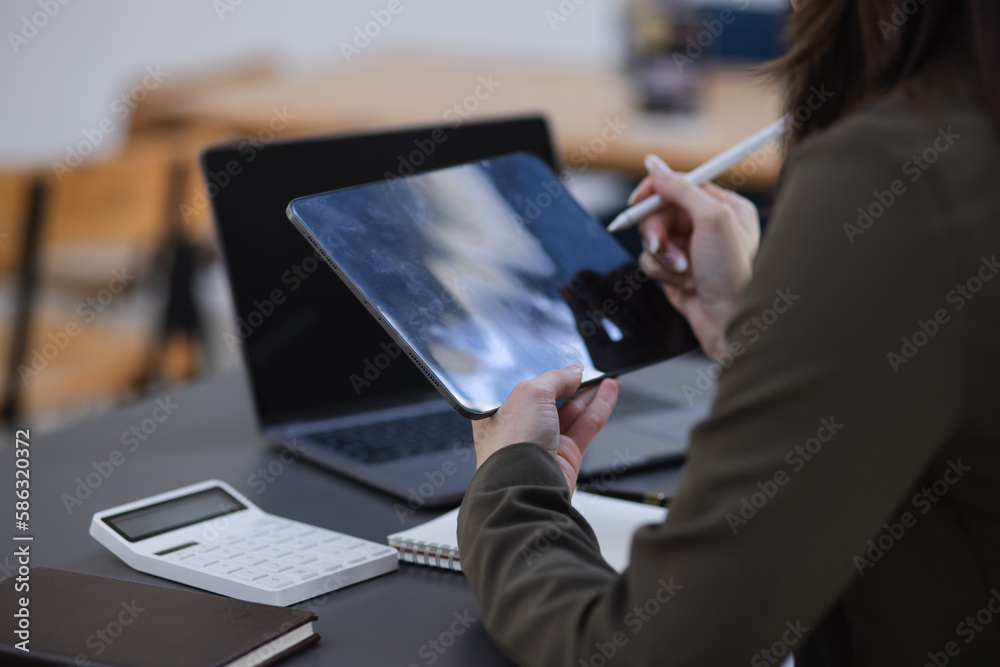 person working on digital tablet with laptop.