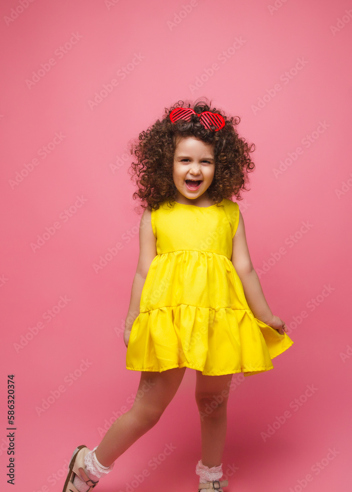 portrait of a girl in a yellow dress cute attractive cute cheerful cheerful little girl .isolated pink background. portrait of a girl in a yellow dress cute attractive cute cheerful cheerful little girl .isolated pink background.