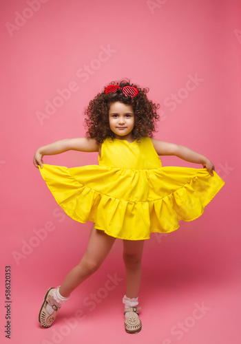 portrait of a girl in a yellow dress cute attractive cute cheerful cheerful little girl .isolated pink background.