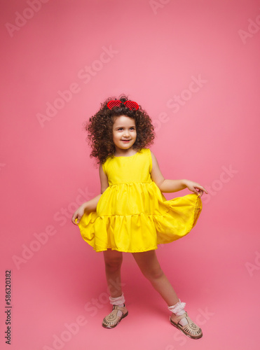 portrait of a girl in a yellow dress cute attractive cute cheerful cheerful little girl .isolated pink background.