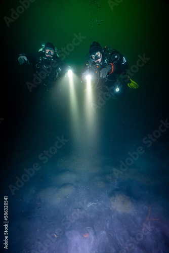 Zwei Taucher am dunklen Seeboden eines Steinbruchs © Yannick