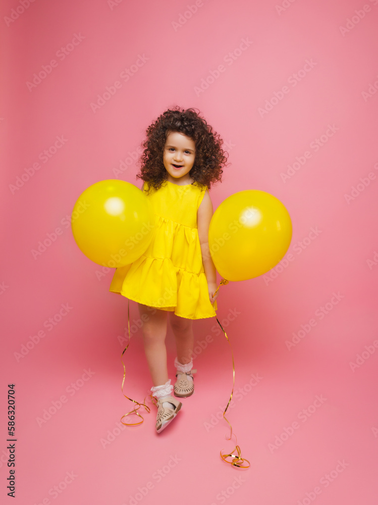 Portrait of a cheerful little girl isolated on a pink background, holding a bunch of colorful balloons, posing. Portrait of a cheerful little girl isolated on a pink background, holding a bunch of colorful balloons, posing.