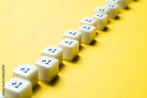 Sequential chain of blocks with plus one. Sequence. Arithmetic progression. Add one more. Increase and growth. A series concept. Accumulation process. Continuation. Sequential addition to the sum.