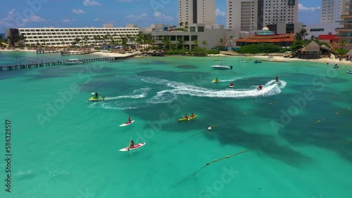 Aerial view of riding people on jet ski (personal watercraft) and Stand up paddle (SUP). Caribbean beach on Cancun hotel zone, Mexico.