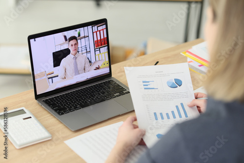 Woman talks to business partner via video call in office