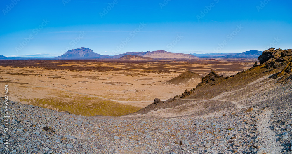 Panoramic over a hiking trail at Icelandic landscape of colorful volcanic caldera Askja, in the middle of volcanic desert in Highlands, with red, turquoise volcano soil and blue sky, Iceland.