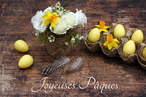 Carte de voeux Joyeuses Pâques : bouquet de fleurs avec des oeufs de Pâques sur un fond de bois. photo