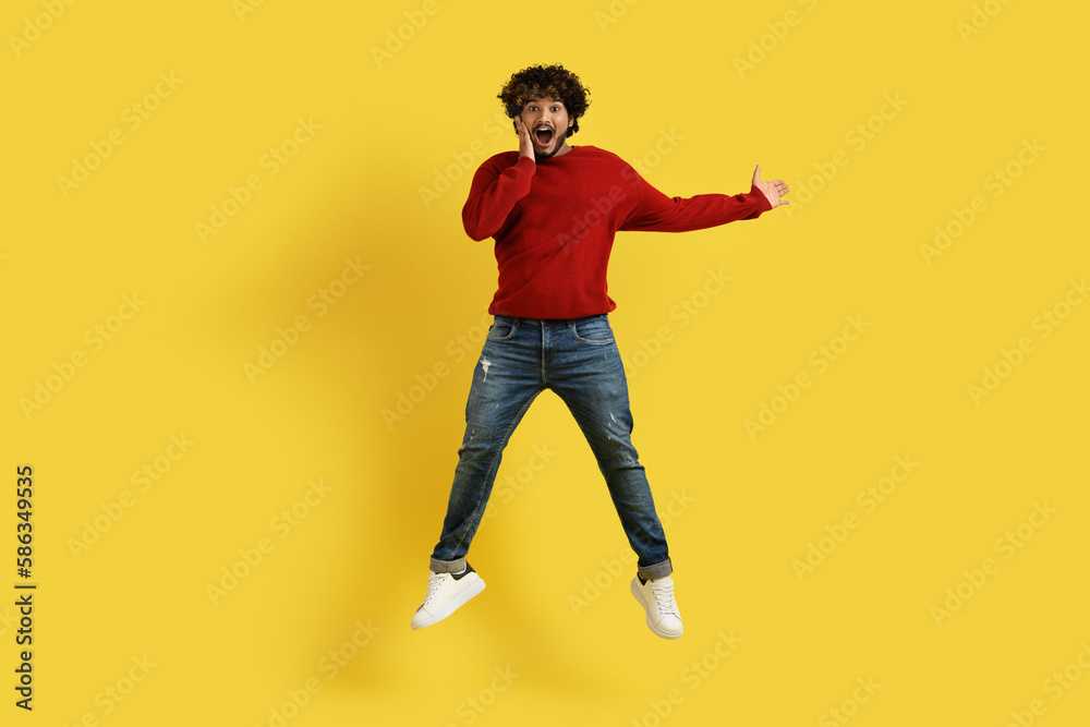 Amazed young hindu guy showing copy space on yellow Amazed young hindu guy showing copy space on yellow