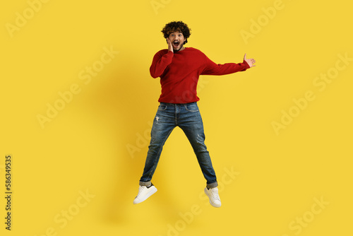 Amazed young hindu guy showing copy space on yellow