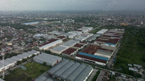 Aerial footage of warehouses complex area with urban cityscape view next to it
