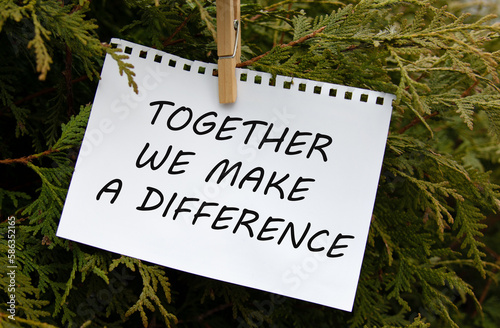 TOGETHER WE MAKE A DIFFERENCE - words on white paper with clothespin on a green background of branches © Zhanna