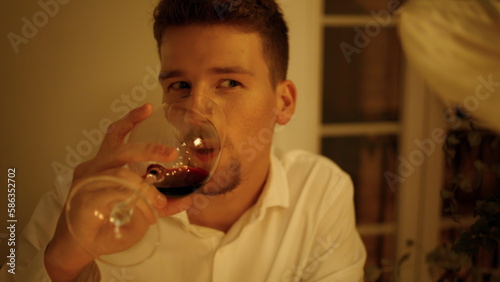 Handsome man tasting wine at romantic date room. Unshaven guy drinking alcohol