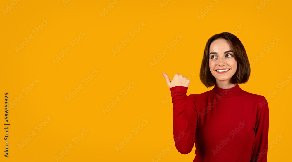 Cheerful pretty young lady in red pointing at empty space Cheerful pretty young lady in red pointing at empty space