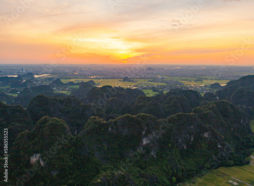 Aerial top view of fresh paddy rice  green agricultural fields with mountain hills valley in countryside or rural area of Ninh Binh  in Asia  Vietnam. Nature landscape background.