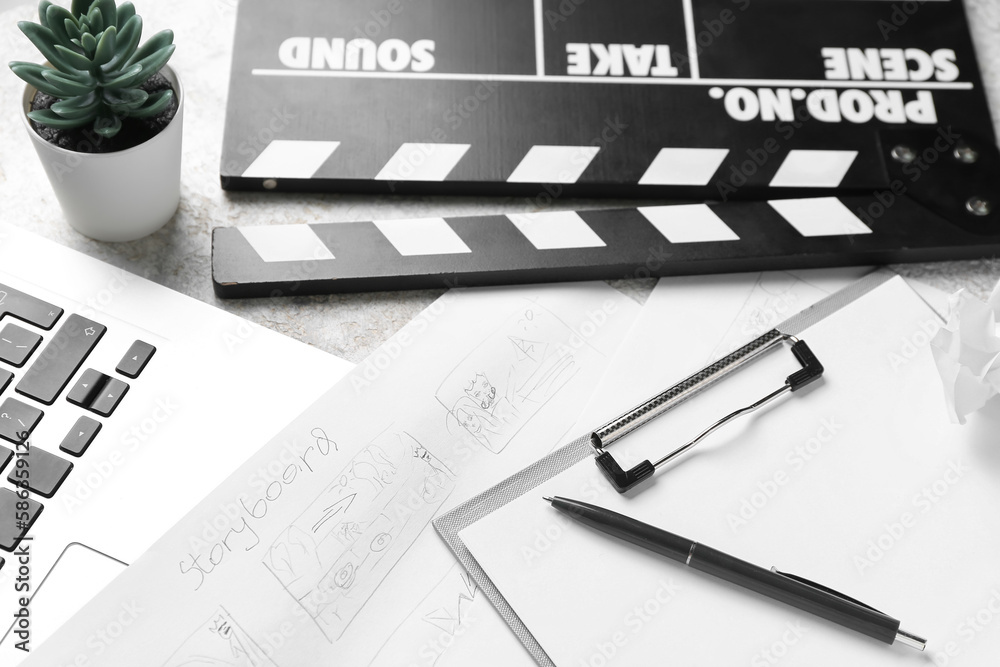 Fototapeta premium Clipboard with storyboard, laptop and movie clapper on grunge background, closeup
