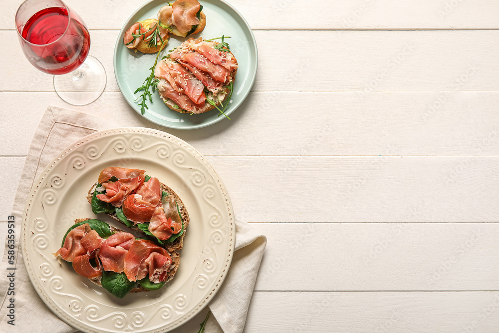 Plates of tasty bruschettas with ham on white wooden background Plates of tasty bruschettas with ham on white wooden background