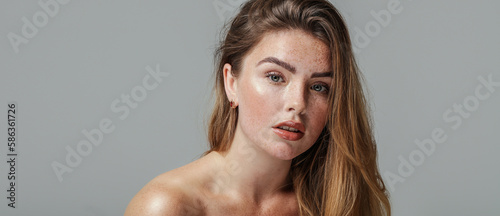 Pretty female model with natural freckled face and shoulder. Beauty woman looking a the camera. Healthy skin concept.