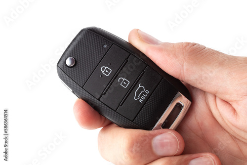 A man's hand holds the car key isolated on a white background close up.