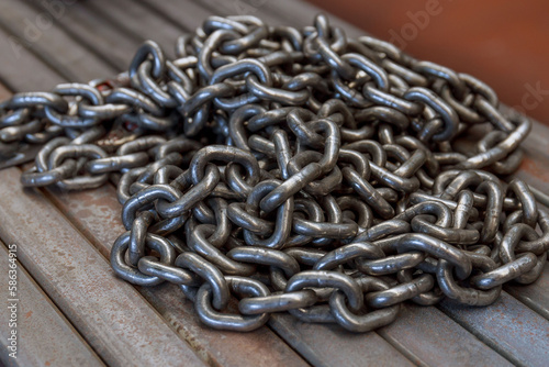 A pile of chain rests on a bundle of coiled metal pipe.