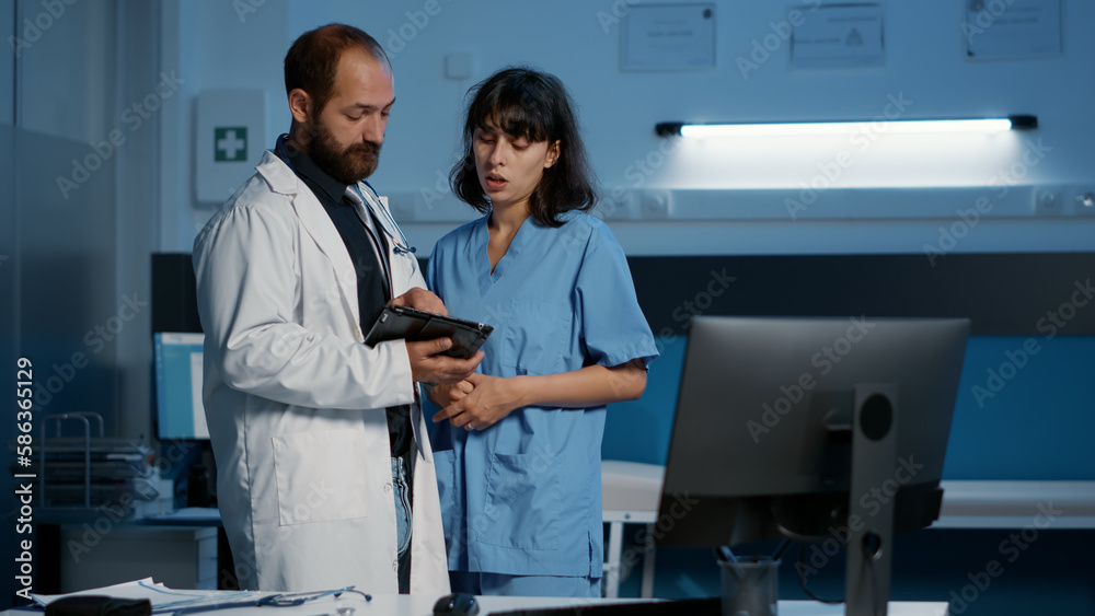 Obraz premium Nurse and doctor looking at medical expertise on tablet computer examining patient disease report discussing health care treatment while working over hours in hospital office. Medicine concept