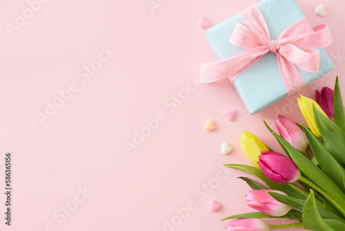Flat lay photo of giftbox bouquet of flowers yellow pink tulips colorful hearts on isolated pastel pink background with empty space. Happy Mother's Day idea © Goncharuk film