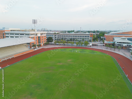 Aerial top view of soccer football sport recreation field ground, national stadium with university or college school campus buildings. Urban city town in Asia. Green court arena.