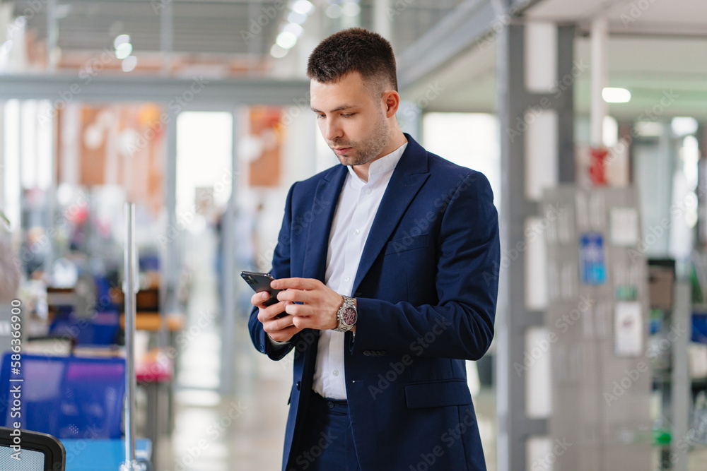 a man in a blue business suit with a phone in hand in the coworking office. a man in a blue business suit with a phone in hand in the coworking office.