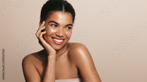 Beauty woman with perfect skin, applies daily care cream, moisturizer, brown background photo
