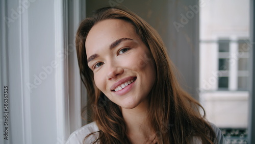 Cheerful woman smiling camera at home portrait. Positive girl playing hair